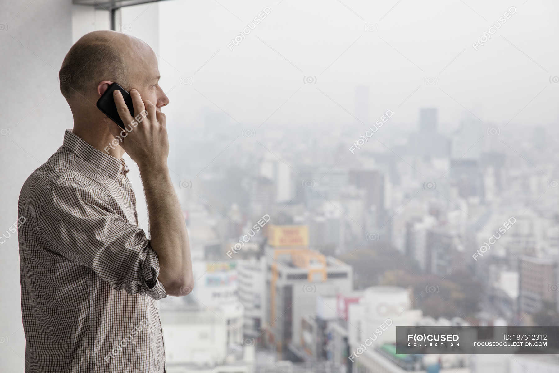 Man talking on phone and looking through window — baldness, mist