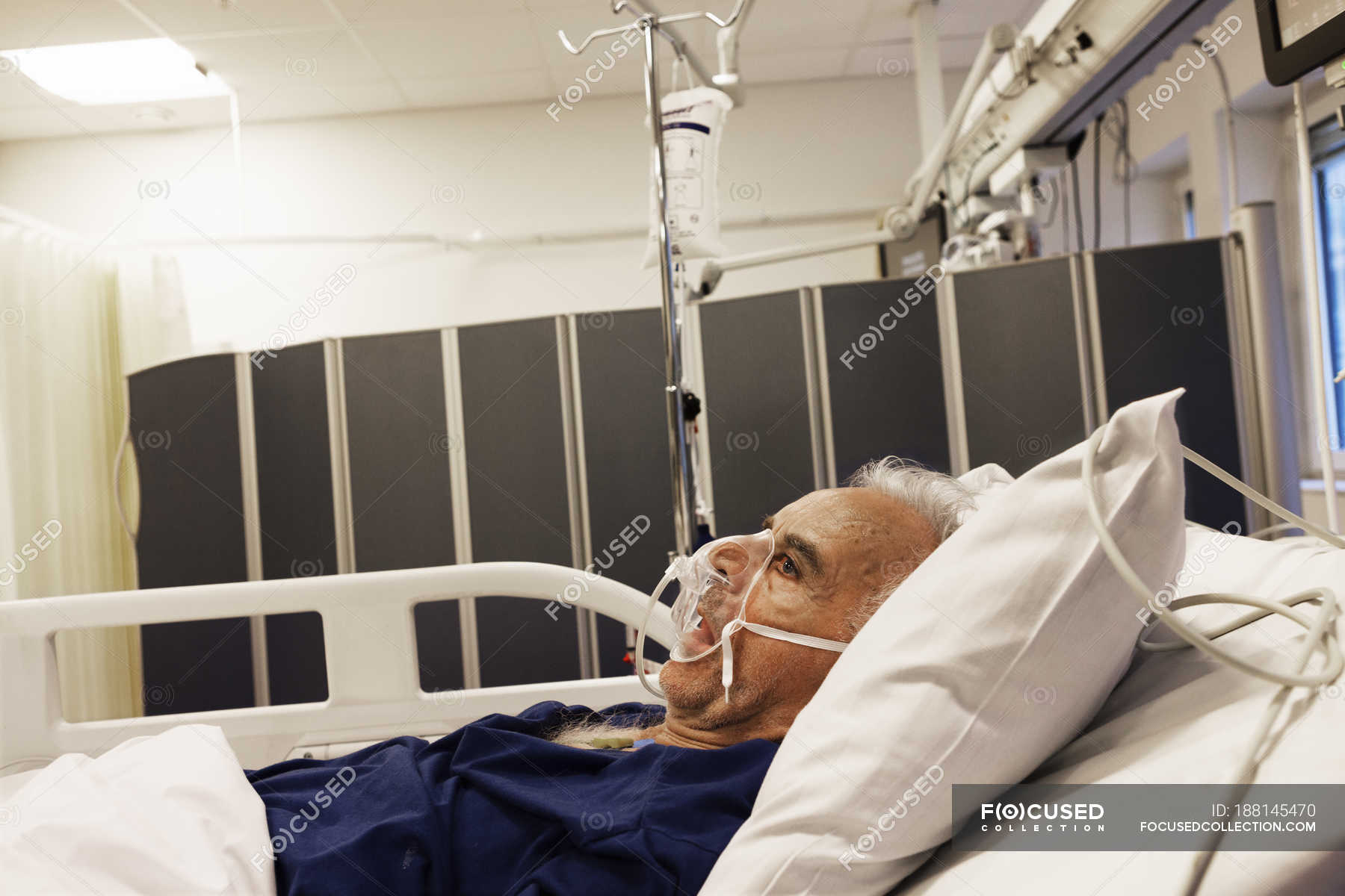 senior-man-lying-down-on-hospital-bed-european-illness-stock-photo