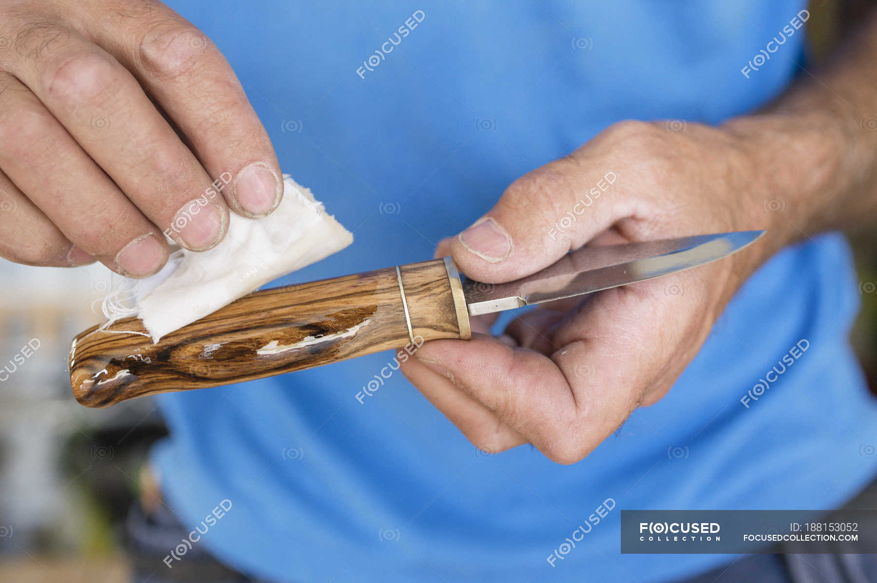 Man oiling wooden knife, focus on foreground — Human Hands, close up Stock Photo 188153052