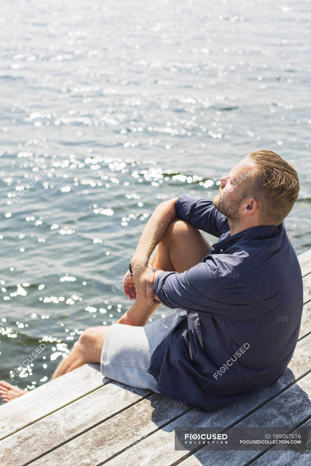 Man sunbathing on jetty, focus on foreground — sitting, male - Stock ...