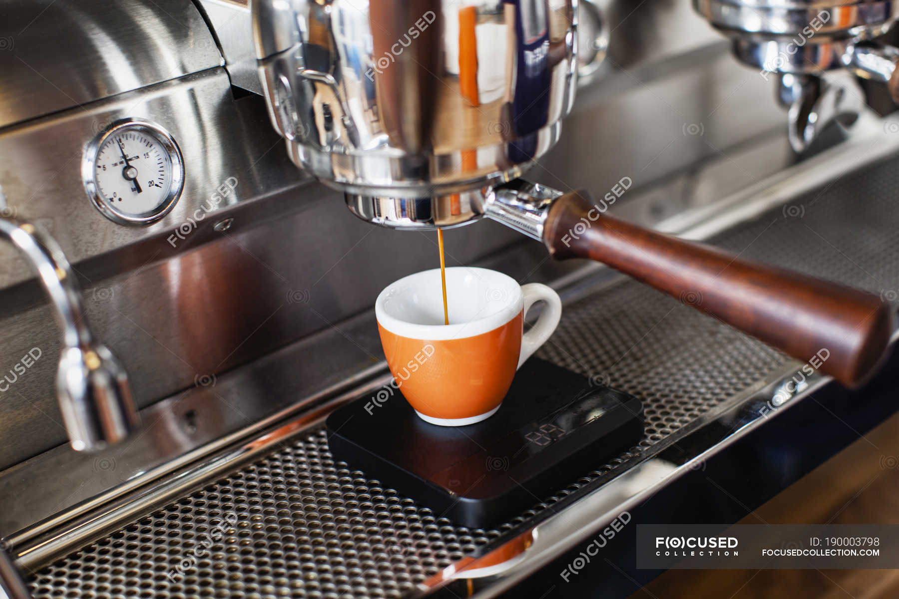 Closeup of espresso maker, differential focus — daytime, coffee cup