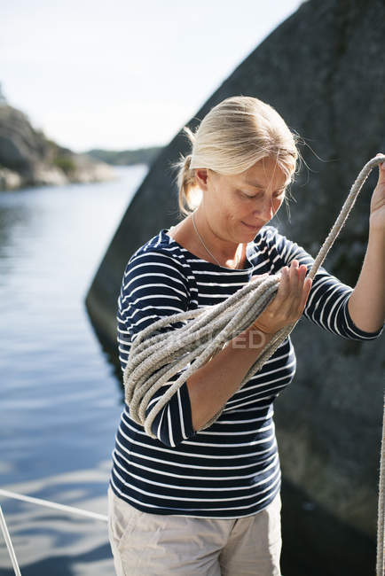 Woman carrying rope on deck of boat — Stock Photo