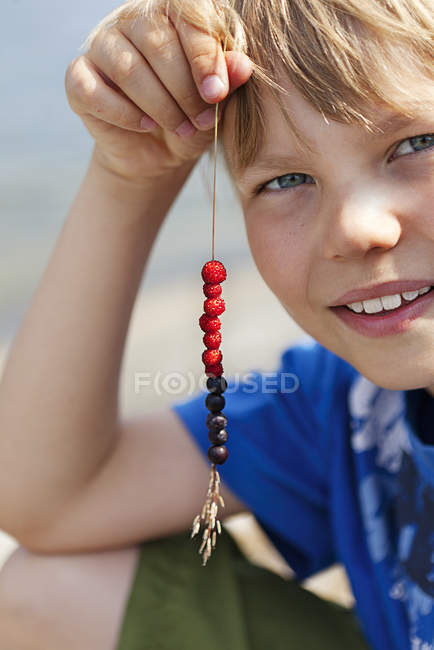 Boy holding straw with berries, focus on foreground — Stock Photo