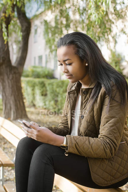 Vue latérale de adolescent fille textos dans le parc — Photo de stock