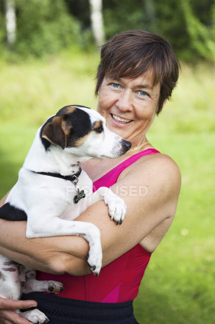 Mujer sosteniendo perro al aire libre, enfoque selectivo - foto de stock