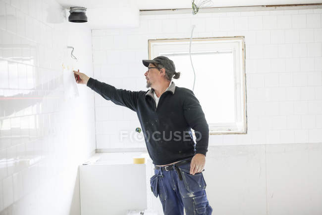 Worker in baseball cap renovating house — Stock Photo
