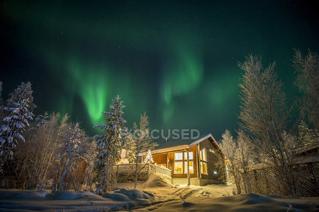 Wohnhaus unter Polarlichtern beleuchtet Himmel — Stockfoto