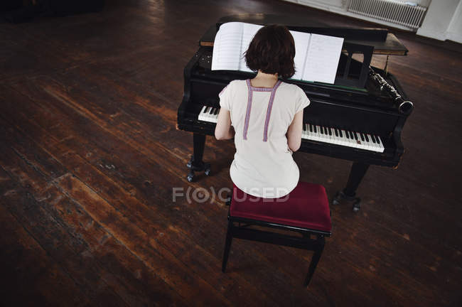 Vista posteriore della donna che suona il pianoforte — Foto stock