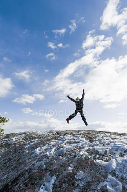 Girl jumping over rock against sky — Stock Photo