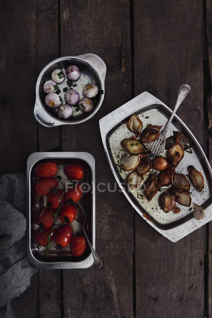 Top view of baked tomatoes, shallots and garlic in baking dishes — Stock Photo
