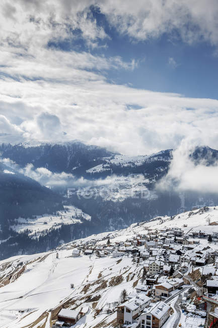 Stadtgebäude mit schneebedeckten Bergen unter bewölktem Himmel — Stockfoto