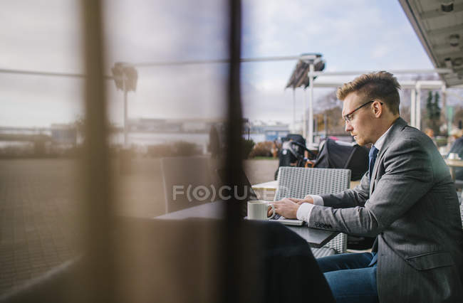 Businessman working at outdoor cafe, focus on background — Stock Photo