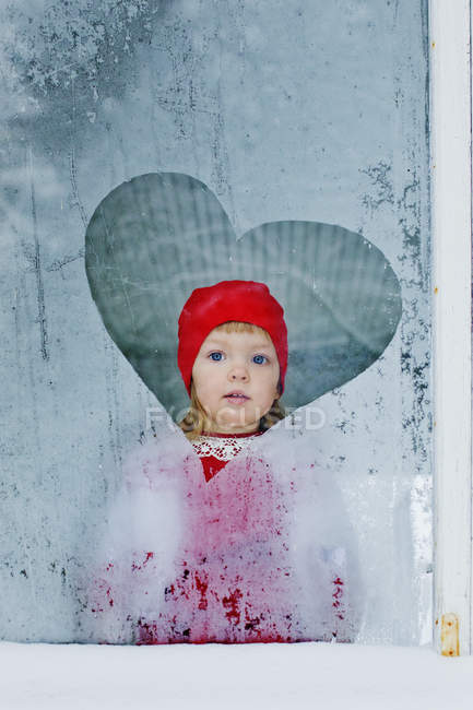 Портрет девушки, смотрящей в замороженное окно — стоковое фото
