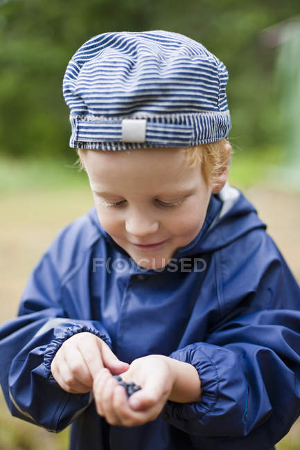 Boy with handful of bilberries, selective focus — Stock Photo