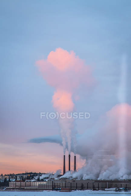 Fumaça que corre de tubos de fábrica ao pôr do sol — Fotografia de Stock