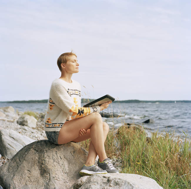 Mujer usando tableta digital en la playa, enfoque selectivo - foto de stock