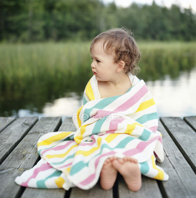 Porträt eines Mädchens in Handtuch gehüllt auf Steg sitzend, differenzieller Fokus — Stockfoto