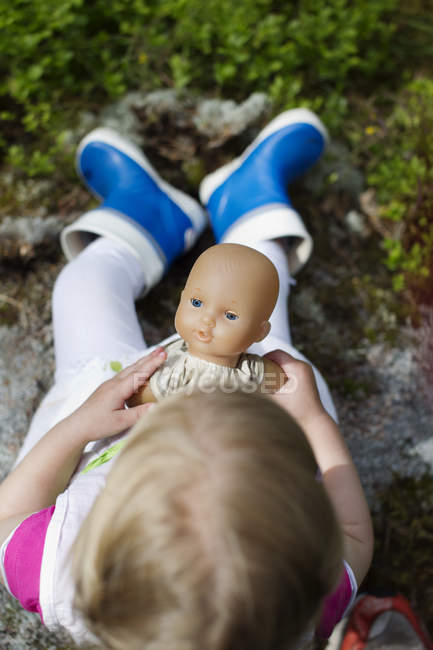 Menina brincando com boneca na floresta, foco diferencial — Fotografia de Stock