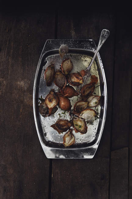 Roasted shallots in baking tin on wooden table — Stock Photo