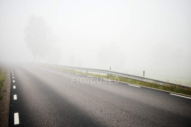 Strada asfaltata segnalata coperta di nebbia — Foto stock