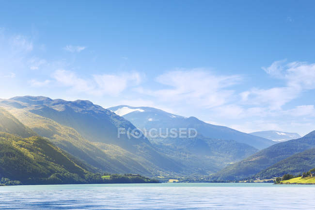 Vista de verdes montañas cubiertas bajo el cielo azul - foto de stock