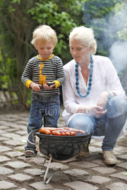 Мама з хлопчиком дивиться на гриль для барбекю, вибірковий фокус — стокове фото