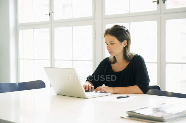 Молода жінка використовує ноутбук в офісі — стокове фото