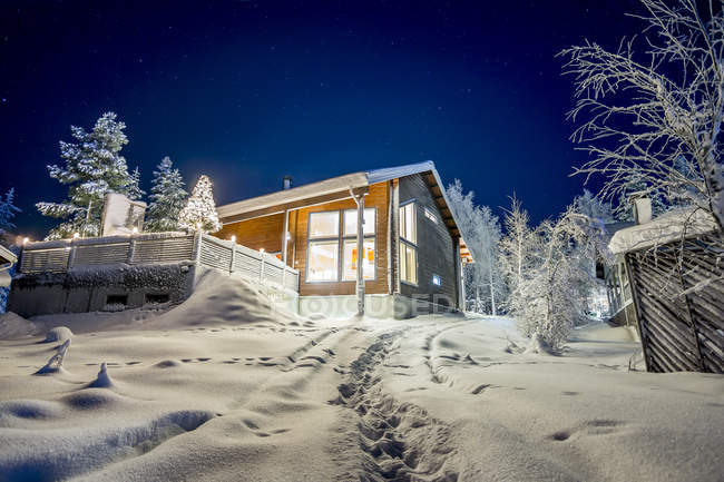 Chalet sur colline enneigée éclairée la nuit — Photo de stock