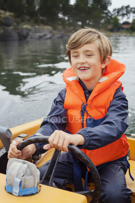 Front view of boy steering motor boat — Stock Photo