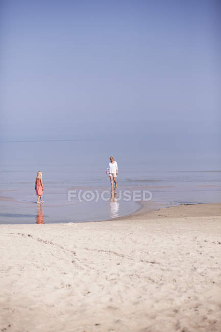Mother and daughter standing in beach shoals — Stock Photo