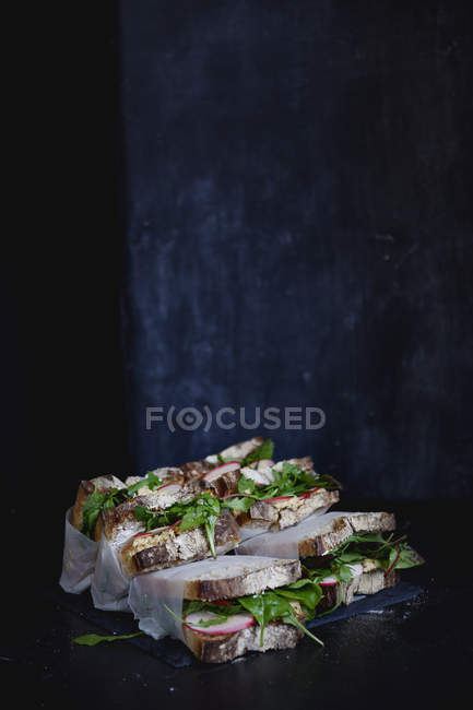 Загорнуті бутерброди з овочами в зелені на темному фоні — стокове фото