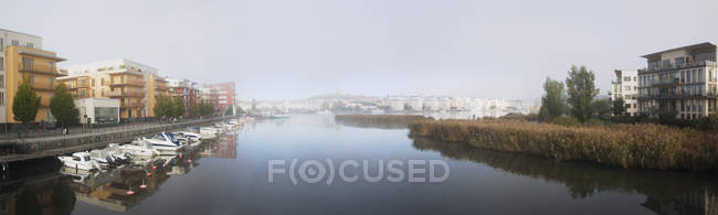 Panoramic view of buildings on riverbanks and moored boats — Stock Photo