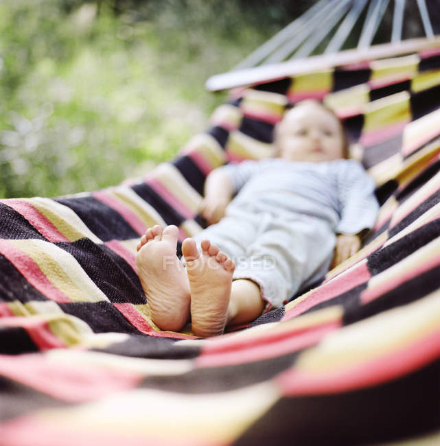 Baby girl lying on hammock, focus on bare feet — Stock Photo