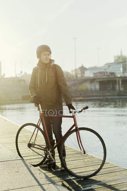 Homem adulto médio de pé com bicicleta de engrenagem fixa no molhe — Fotografia de Stock