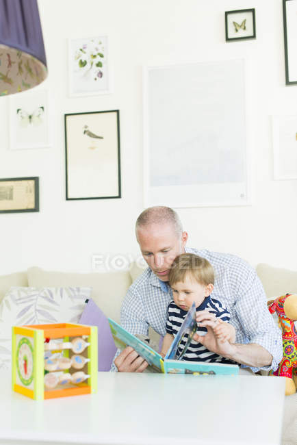 Чоловік читає синові у вітальні — стокове фото