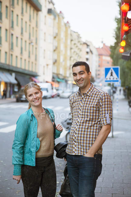 Retrato de pareja sonriente de pie en la calle - foto de stock