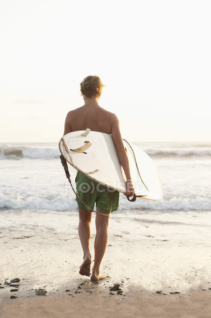 Adolescente com prancha de surf caminhando em direção ao mar na Costa Rica — Fotografia de Stock