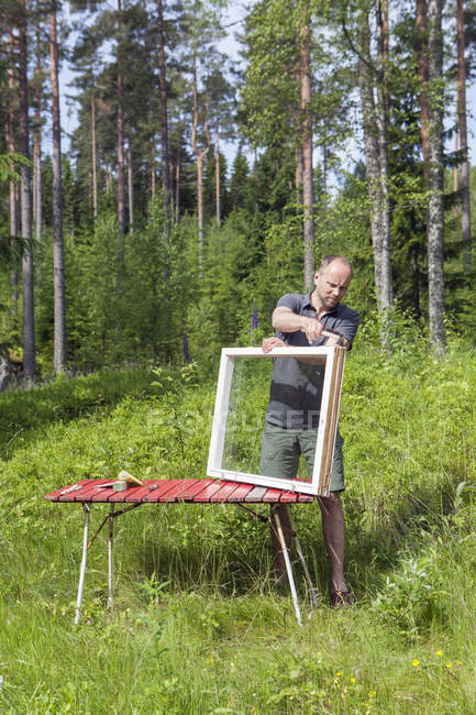 Frontansicht eines Mannes, der an Rahmen im Wald arbeitet — Stockfoto