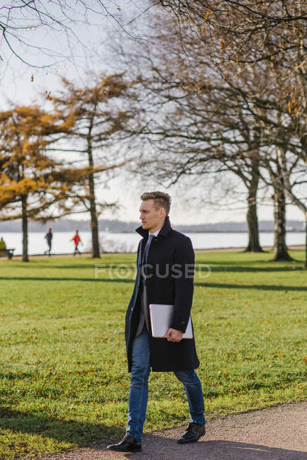 Vista lateral del hombre de negocios caminando en el parque - foto de stock