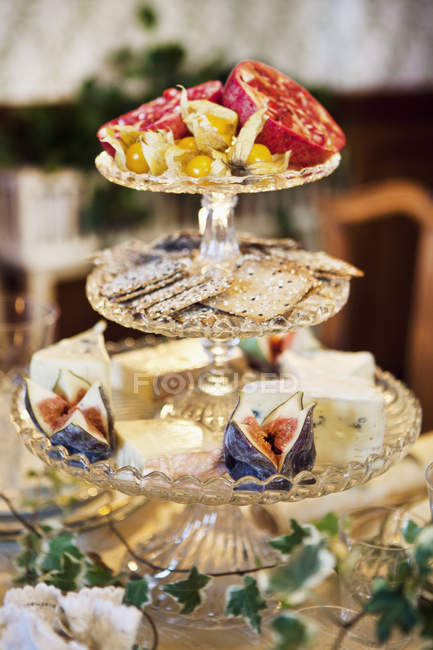 Close up shot of cake stand with fruit, crackers and cheese — Stock Photo