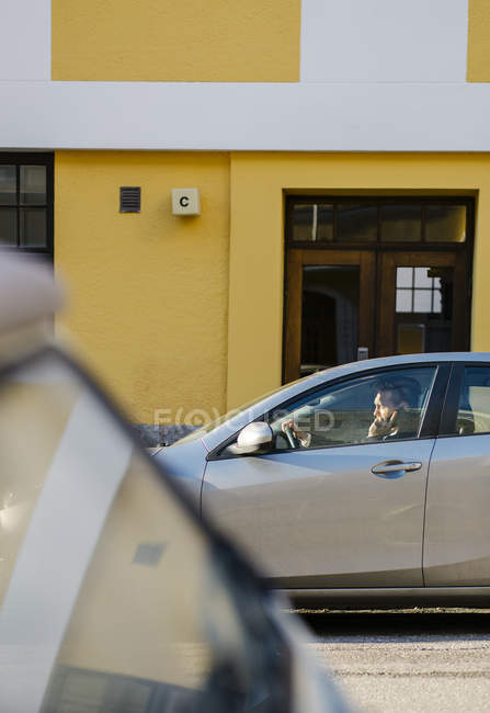 Вид збоку водія автомобіля, що говорить на смартфоні, вибірковий фокус — стокове фото