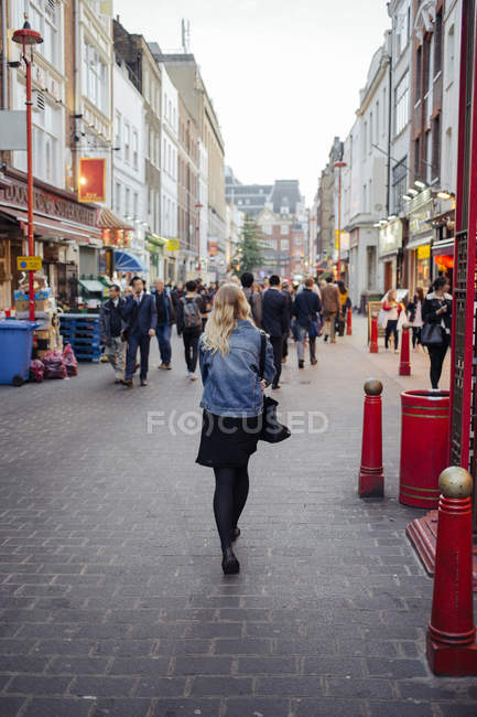 Rear view of young woman walking along street in London — Stock Photo