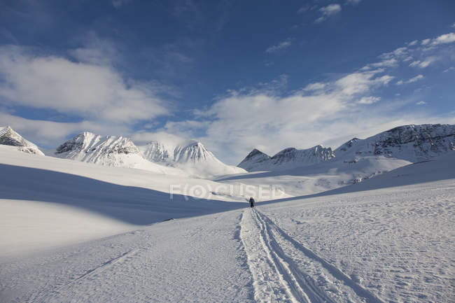 Paisaje de montaña cubierto de nieve con turista lejano - foto de stock