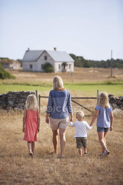 Madre con hijo e hijas caminando en el patio de la granja - foto de stock