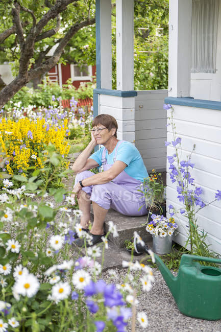 Женщина сидит на крыльце садового дома — стоковое фото