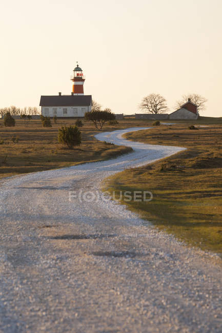 Winding rural road with small house and red lighthouse — Stock Photo