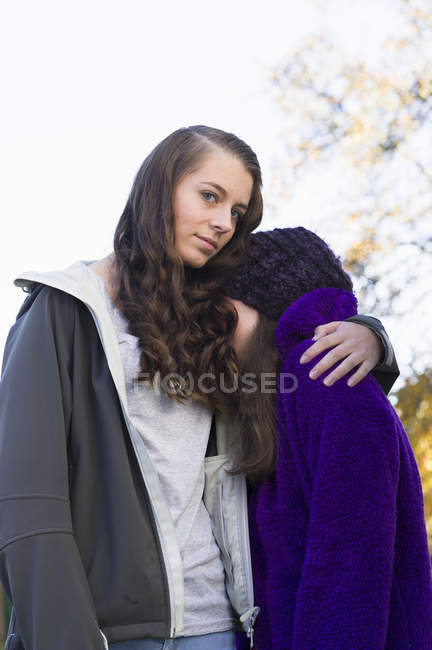 Teenage girl embracing younger friend, focus on foreground — Stock Photo