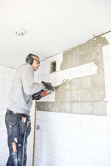 Giovane uomo in protettori auricolari ristrutturare casa — Foto stock