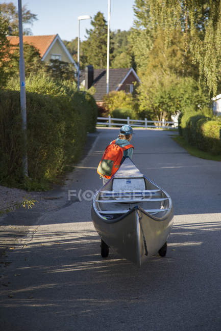 Ragazzo tirando canoa su strada — Foto stock