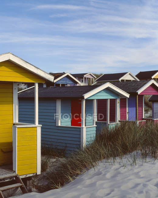 Cabanas coloridas na praia gramada sob o céu azul — Fotografia de Stock